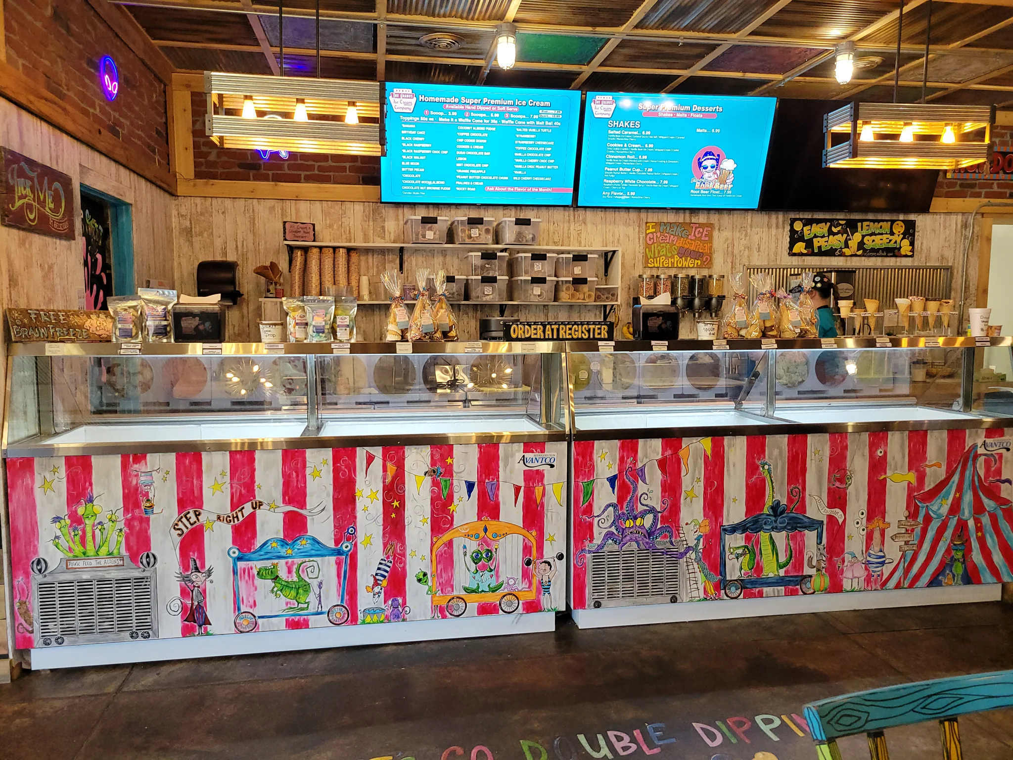 Colorful ice cream shop with a decorated counter and menu screens.