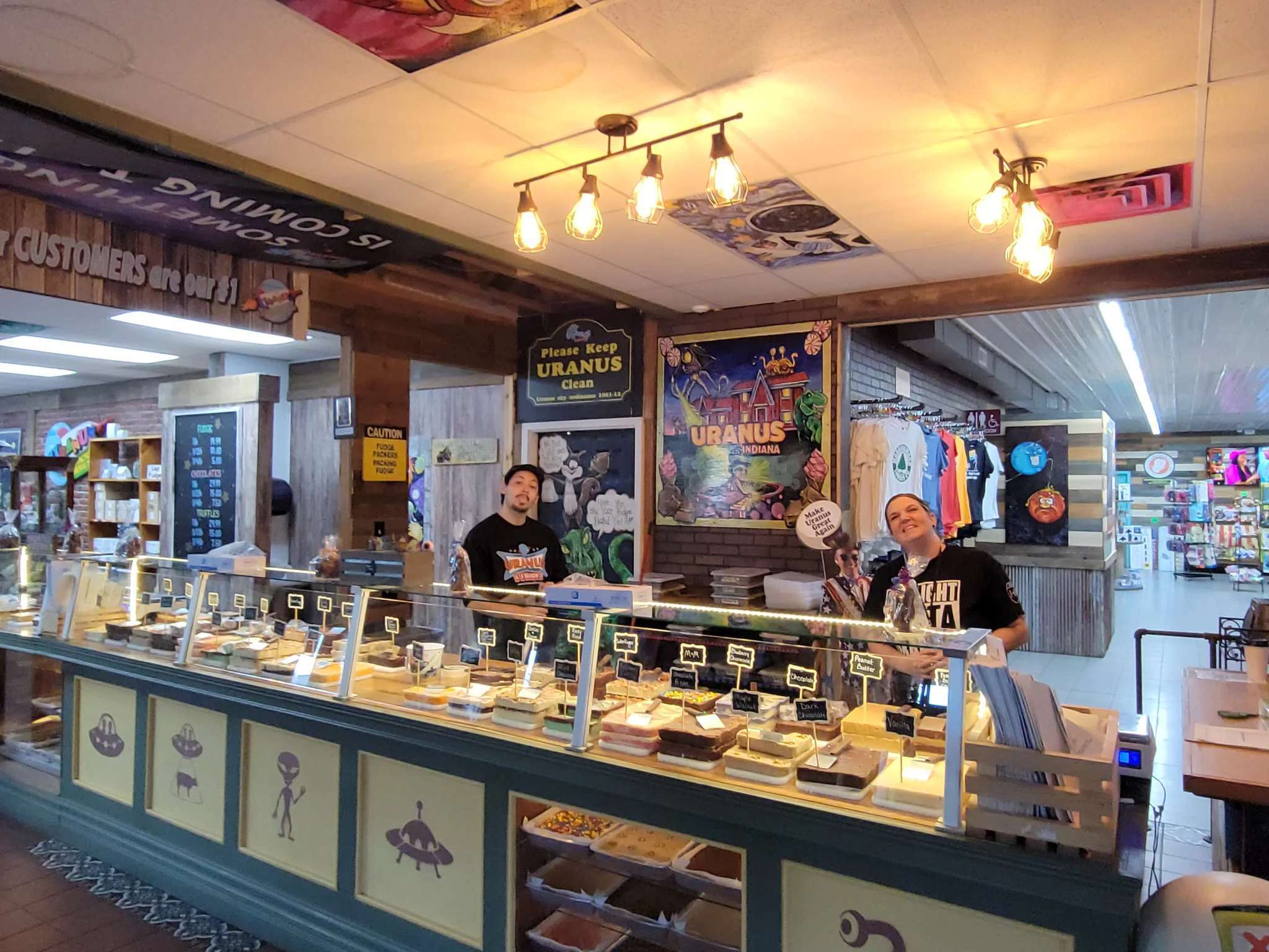 Two people behind a display counter in a market with various products.