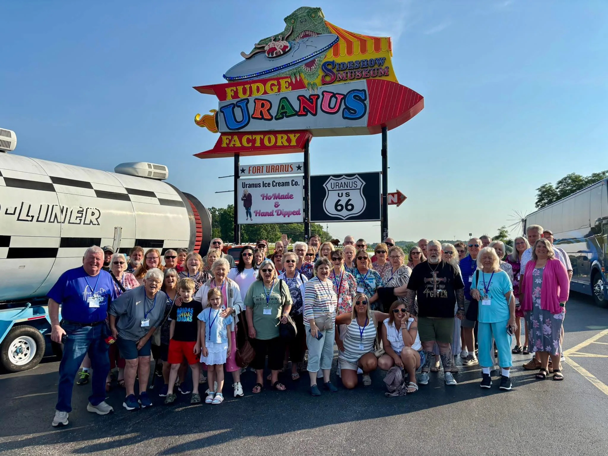Group photo in front of the colorful neon-sign for Uranus Fudge Factory in Uranus, Missouri.