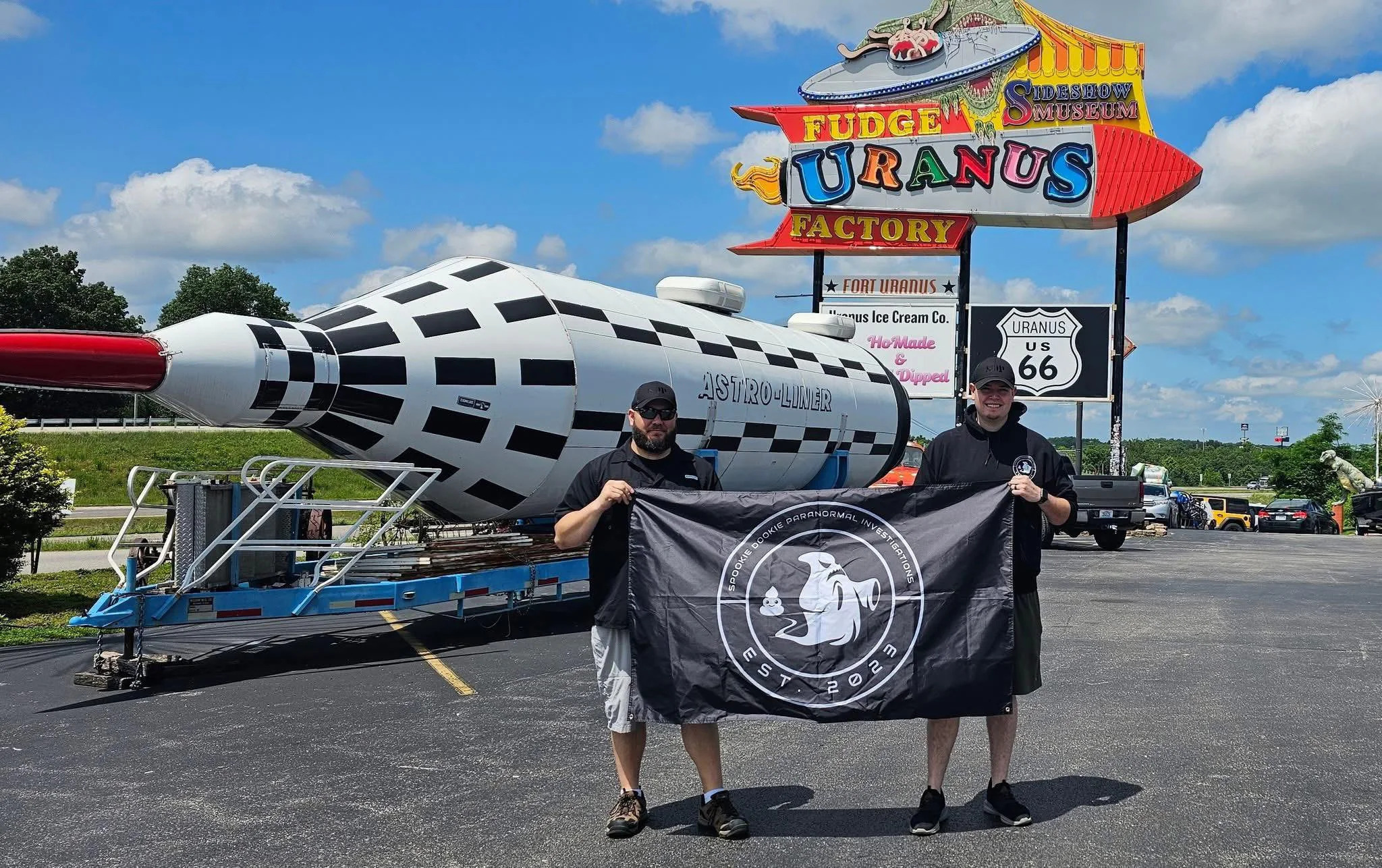 Two men holding a flag in front of a large rocket display.