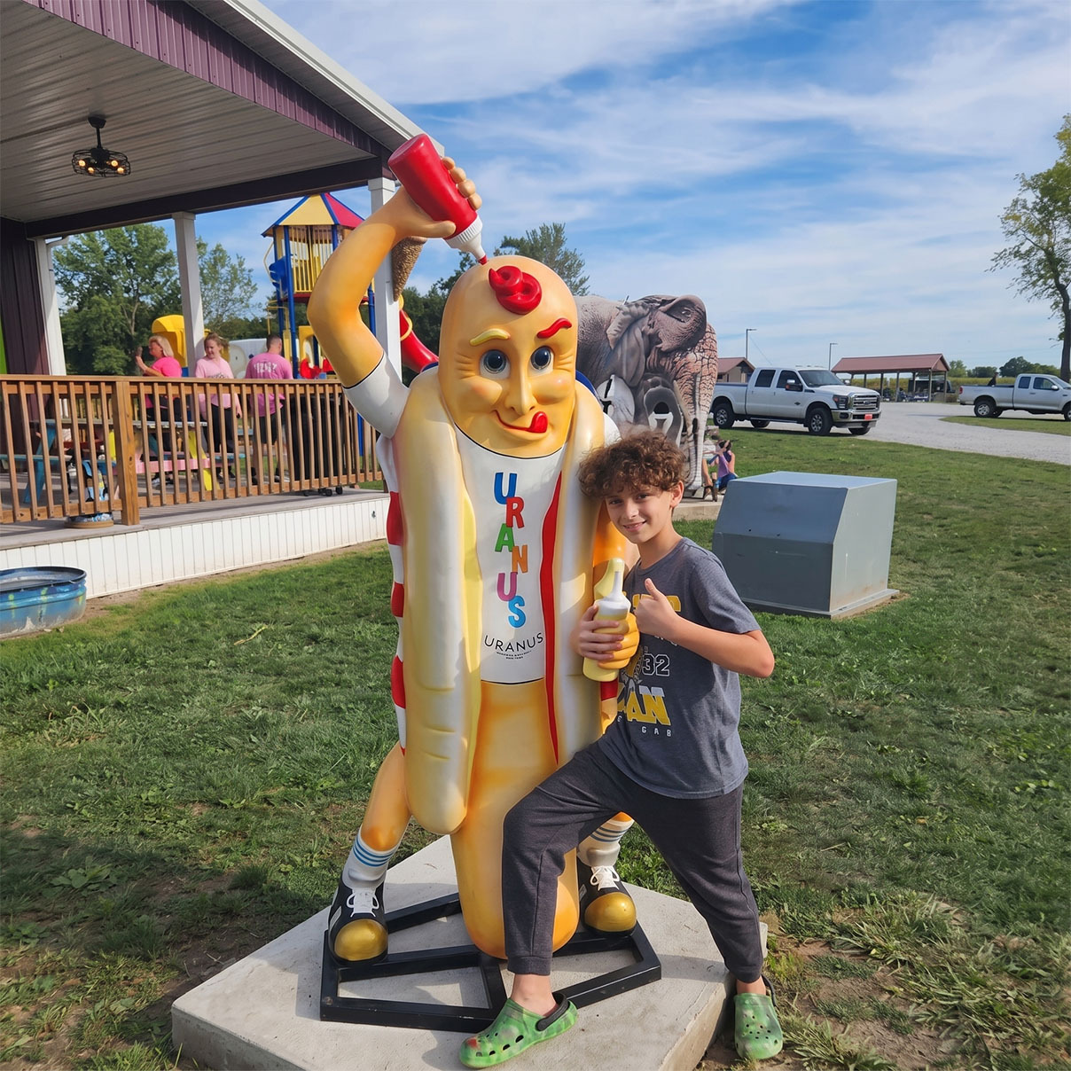 Boy posing with the Uranus Weiners hot dog mascot statue in Anderson, Indiana
