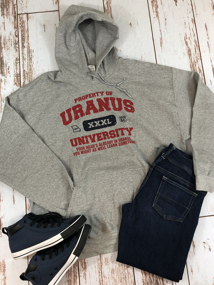 A gray hoodie with a Uranus University graphic laid flat with blue jeans and high-top sneakers